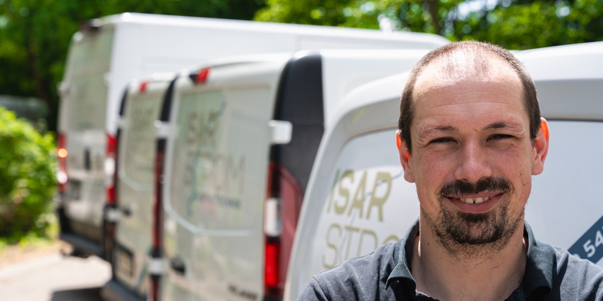 Paul Hellmann, Geschäftsführer von Isarstrom Elektrotechnik, vor den Servicefahrzeugen am Standort Planegg